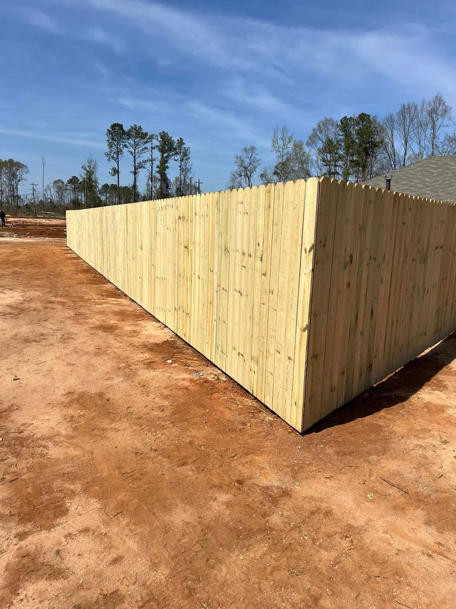 A wooden fence is sitting on top of a dirt field.