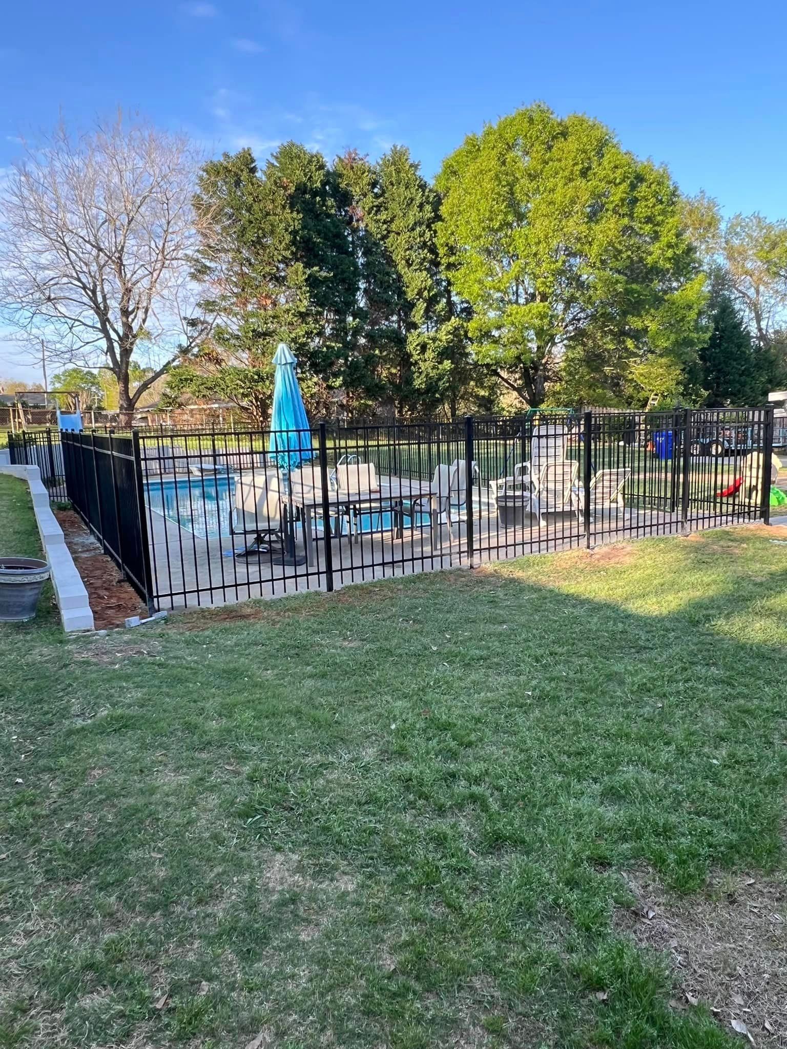 A fence surrounds a swimming pool in a park.