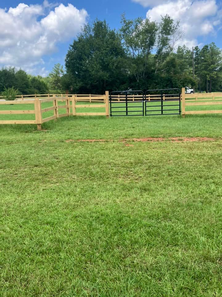 There is a wooden fence in the middle of a grassy field.