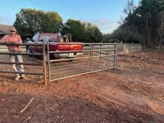 There is a fence in the middle of a dirt field.